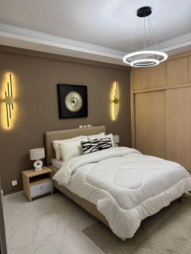 una camera da letto con un grande letto bianco e un lampadario di Adèle résidence a Mandanou