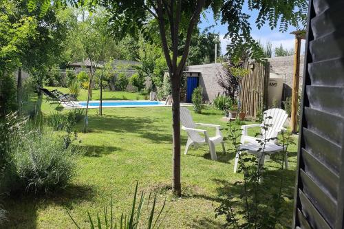 een tuin met twee witte stoelen en een zwembad bij Arrabal.Tupungato in Tupungato