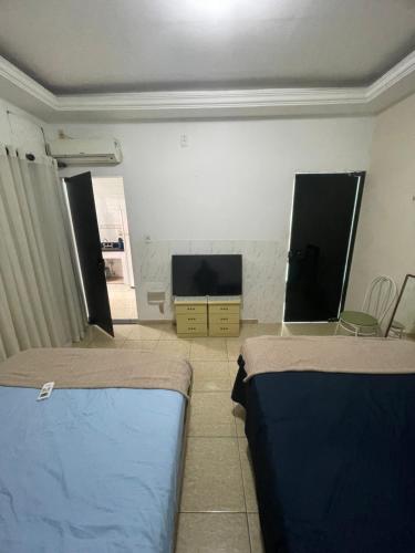 ein Zimmer mit zwei Betten und einem Flachbildfernseher in der Unterkunft Hostel and Party Space! in Três Rios