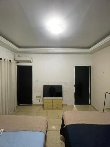 a room with two beds and a flat screen tv at Hostel and Party Space! in Três Rios