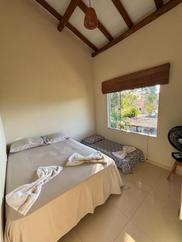 a bedroom with a bed and a window at Vila Floresta - Arraial D'Ajuda in Porto Seguro