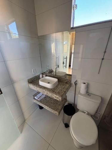 a white bathroom with a toilet and a sink at Vila Floresta - Arraial D'Ajuda in Porto Seguro