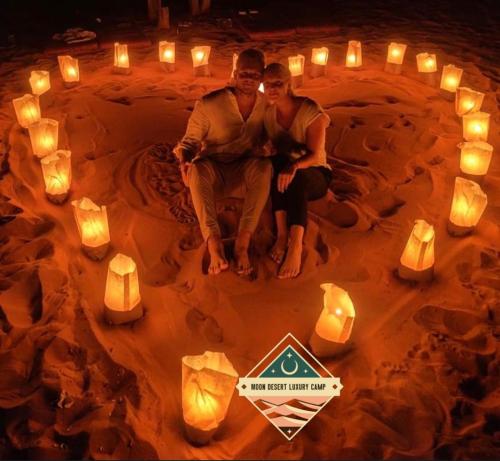 a man and woman sitting in a circle of candles at Moon Desert Luxury Camp in Wadi Rum