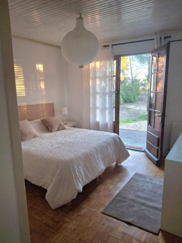 a bedroom with a bed and a sliding glass door at LES CIGALINES Chalet au calme in Fabrezan