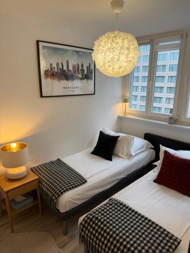 zwei Betten in einem Zimmer mit einer Lampe und einem Tisch in der Unterkunft Apartament Centrum Warszawy Pereca in Warschau