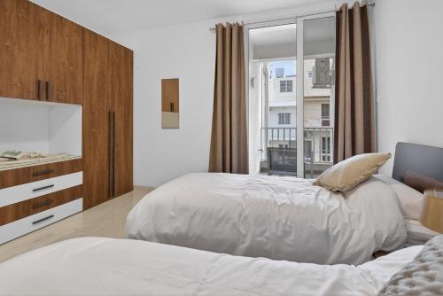 a bedroom with two beds and a large window at Contemporary Retreat in St. Paul's Bay