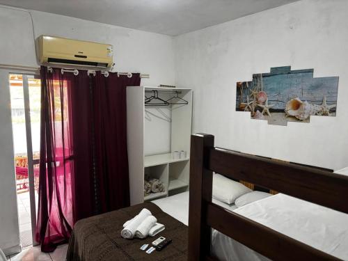 een slaapkamer met een bed en een rood gordijn bij Pousada Ju&Ju à 400 mts DA PRAIA in Pontal do Paraná