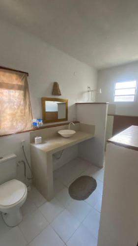 een badkamer met een toilet, een wastafel en een spiegel bij Casa Bari in Jericoacoara