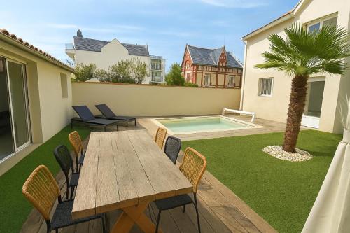 eine Terrasse mit Tisch und Stühlen und ein Swimmingpool in der Unterkunft Villa Ô Dunes in Châtelaillon-Plage