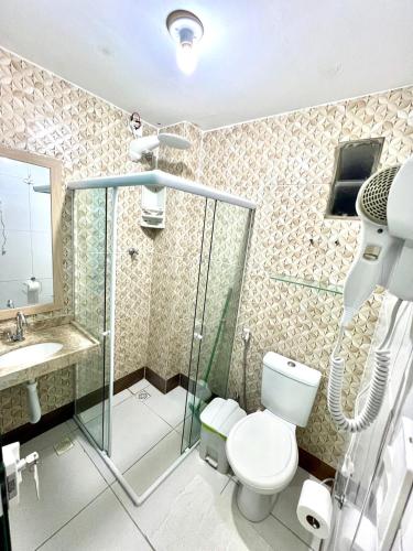 a bathroom with a toilet and a shower and a sink at Flats Corais in Maragogi