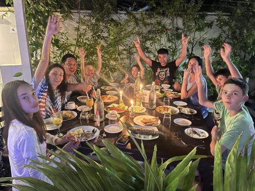 a group of people sitting around a table raising their hands at Oceanvine in Mahibadhoo