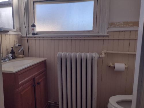 La salle de bains est pourvue d'un radiateur, d'un lavabo et d'une fenêtre. dans l'établissement Ventnor Island Beach House, à Ventnor City