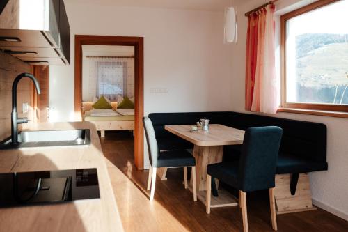una cucina con tavolo, sedie e lavandino di Prestihof a San Vigilio Di Marebbe