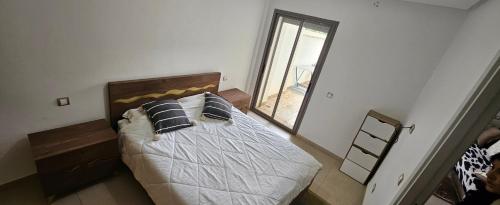 a bedroom with a bed with pillows and a window at Résidences Mansbay Jasmin in Mansouria