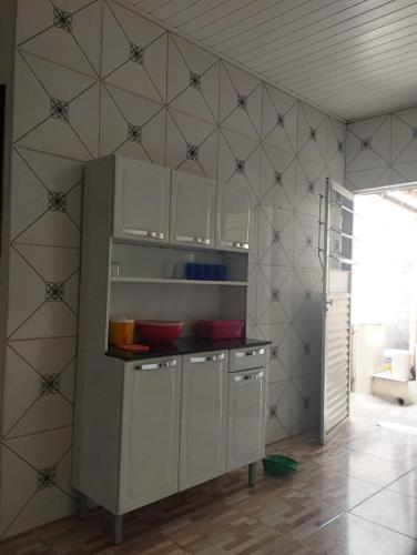 een keuken met witte kasten en een betegelde muur bij Temporada Recanto Girassol in Piranhas
