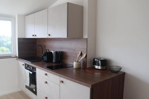 eine Küche mit weißen Schränken und einer Holzarbeitsplatte in der Unterkunft Appartement Le nid sur l'Ain in Champagnole