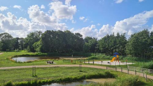 een park met een speeltuin met een glijbaan en een vijver bij Haus Lüchtje Jade in Sehestedt
