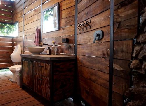 a bathroom with a wooden wall with a sink and a toilet at Libra Eco-Adventure Hostel in El Pescadero