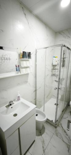 a white bathroom with a shower and a toilet at Playa de Sant Adrià de Besòs in Sant Adria de Besos