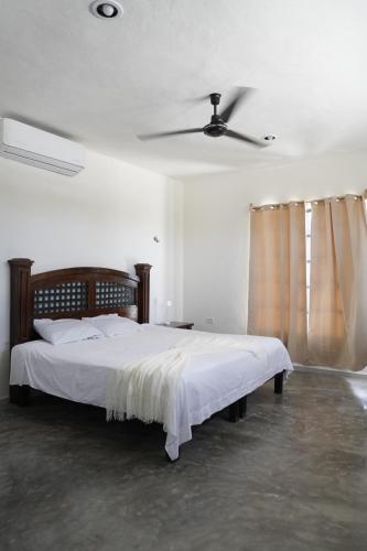 a bedroom with a large bed with a ceiling fan at Casa Calandria in Chicxulub