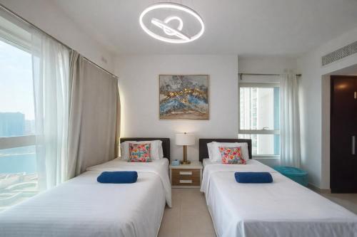 two beds in a room with a window at Exclusive Sea-View 2BR Apartment with Fireworks View in New-year eve in Abu Dhabi