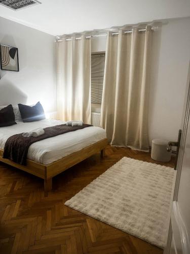 a bedroom with a bed and a rug and curtains at Ember Residence Spacious 2BR Apartment near Eternal Flame in Sarajevo