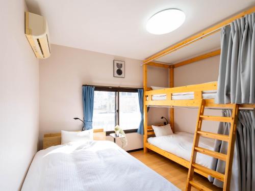 een slaapkamer met twee stapelbedden en een ladder bij ゲストハウス海と石 in Takamatsu