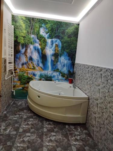 een badkuip in een badkamer met een watervalmuurschildering bij Sava centar apartman in Belgrado