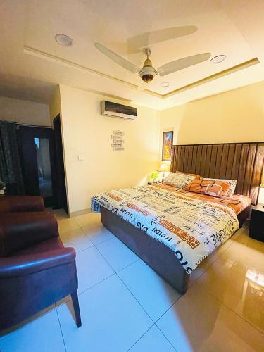 a bedroom with a large bed and a chair at Royal Rooms - Misaq-ul-mall in Faisalabad