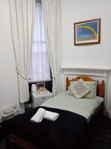 a small bedroom with a bed with a window at The Limes Guesthouse Montrose in Montrose