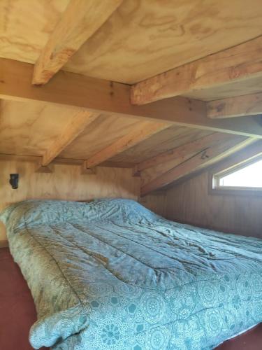 a bed in a room with a wooden ceiling at La petite cabane de Putemun in Castro
