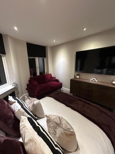 a bedroom with a large bed with pillows and a flat screen tv at Cozy Studio Flat in Bradford City Centre in Bradford