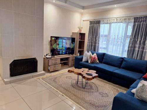un salon avec un canapé bleu et une télévision dans l'établissement Valley Rest, à Mbabane