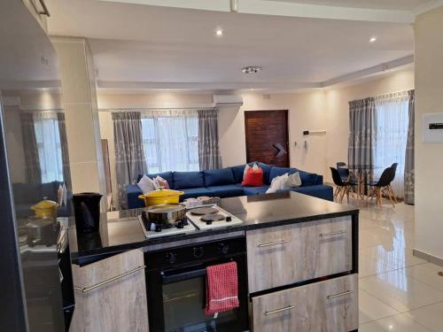 Il comprend une cuisine équipée d'une cuisinière et d'un canapé bleu. dans l'établissement Valley Rest, à Mbabane