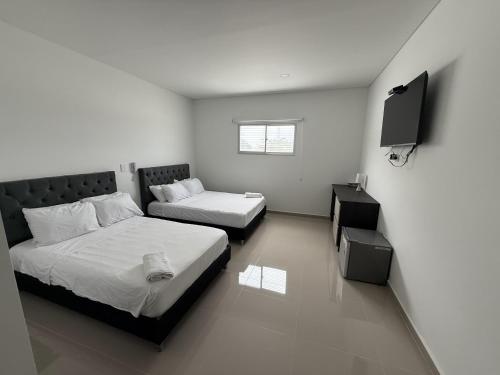 a bedroom with two beds and a television in it at Tierra Bendecida Hotel Boutique in Villavicencio