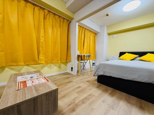 ein Schlafzimmer mit einem Bett und einem Tisch und gelben Vorhängen in der Unterkunft 501札幌駅と大通駅も徒歩圏内な最高な立地最大2名様まで快適にご宿泊可能です in Sapporo