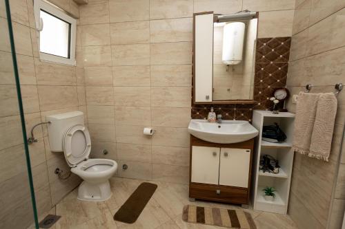 een badkamer met een toilet, een wastafel en een spiegel bij LuxuryHomeUlcinj2 in Ulcinj