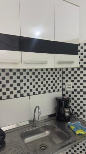 a kitchen counter with a sink and black and white tiles at Suíte Macedônia in Arraial do Cabo
