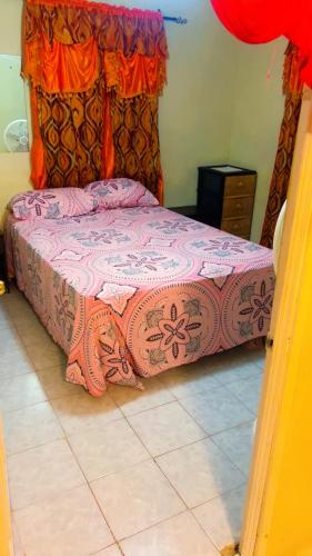 una camera da letto con un letto con copriletto rosa di Tamaras Inn a Christ Church