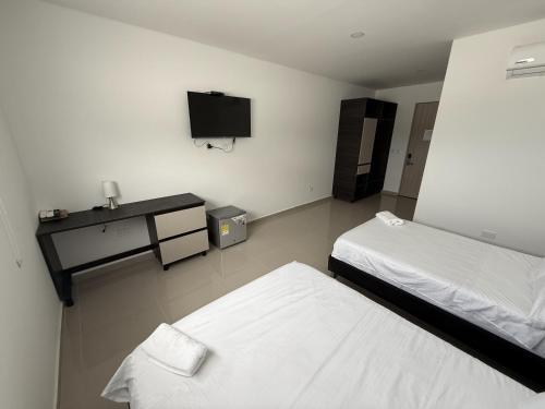 een slaapkamer met twee bedden en een tv aan de muur bij Tierra Bendecida Hotel Boutique in Villavicencio