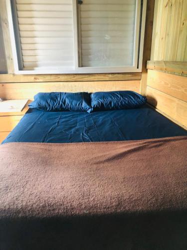 a bed with a blue pillow in a room at Casa Praia in Palhoça