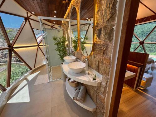 a bathroom with two sinks and a stone wall at Exclusive Cabanas BOLHA LUXO in Serra Negra