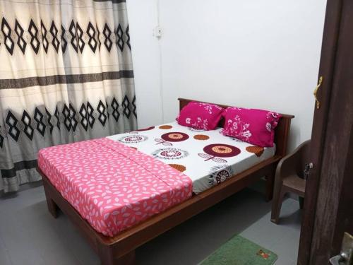 a bedroom with a bed with pink pillows at Titi garage meublé in Yaoundé