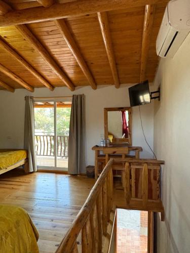 een kamer met een bed, een televisie en een balkon bij Cabañas las Gemelas in Areponapuchi