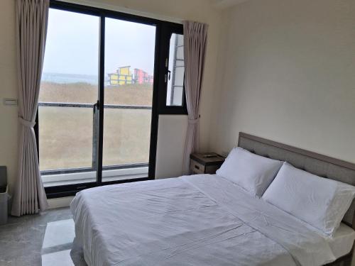 een slaapkamer met een bed en een groot raam bij 星輝漫旅 in Magong