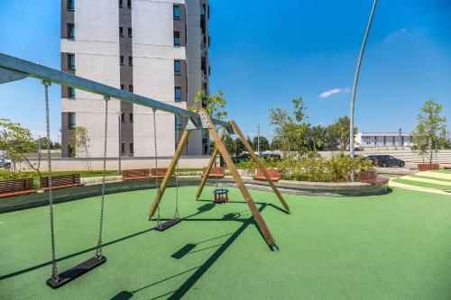 un'altalena in un parco giochi con un edificio di Afi City - București Noi a Bucarest