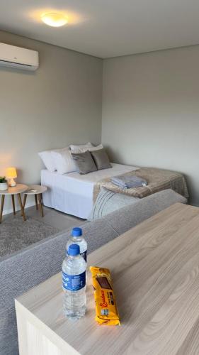 a bottle of water on a table with two beds at Loft Centralíssimo com Garagem in Pelotas