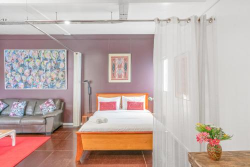 a bedroom with a bed and a couch at ArtHOUSE Beachfront Accommodation in Emerald Beach