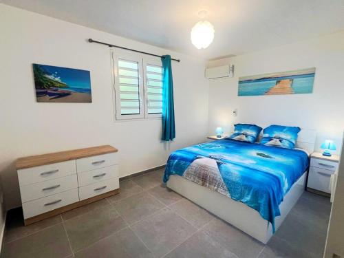 una camera da letto con un letto blu e una finestra di Belle petite maison Les Trois-Îlets a Les Trois-Îlets