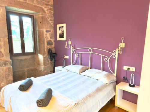 een slaapkamer met een wit bed met paarse muren bij A Casa de Feli in Muros